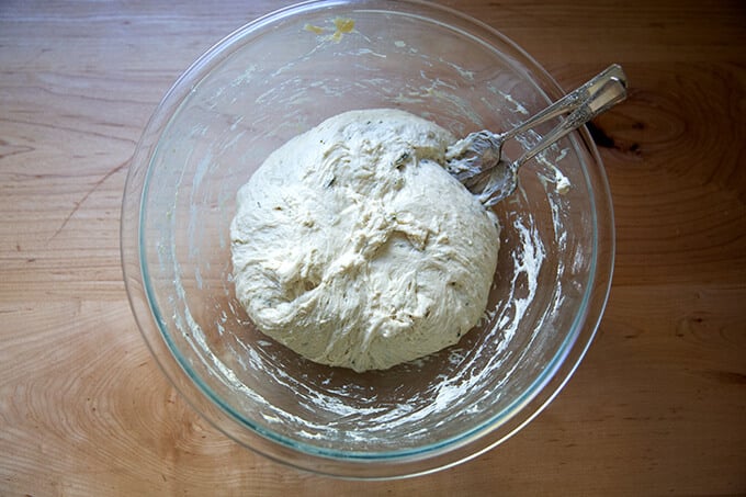 A bowl of no-knead thyme dinner roll dough, punched down.