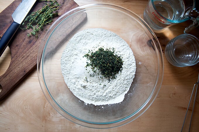 A bowl of flour, salt, sugar, yeast, and thyme.