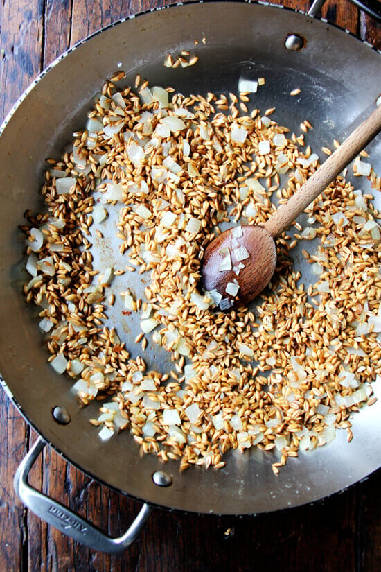 A pan of sautéed onion and pearled farro. 