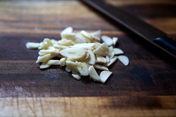 Sliced garlic on a cutting board.