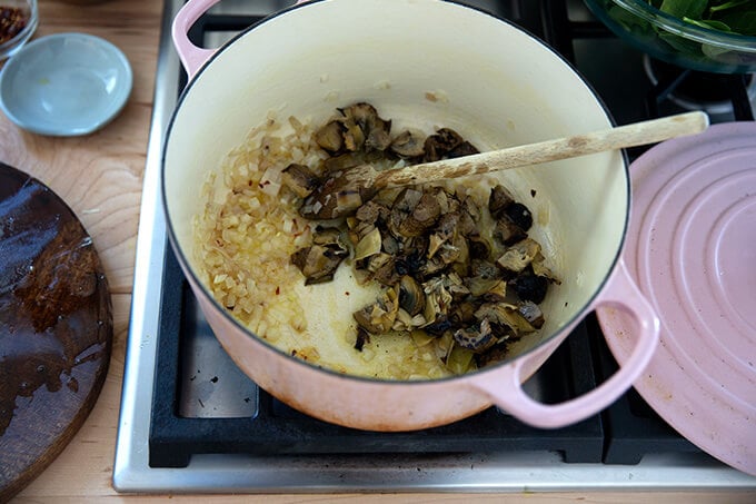 Diced artichoke hearts in a pot with sautéed shallots.