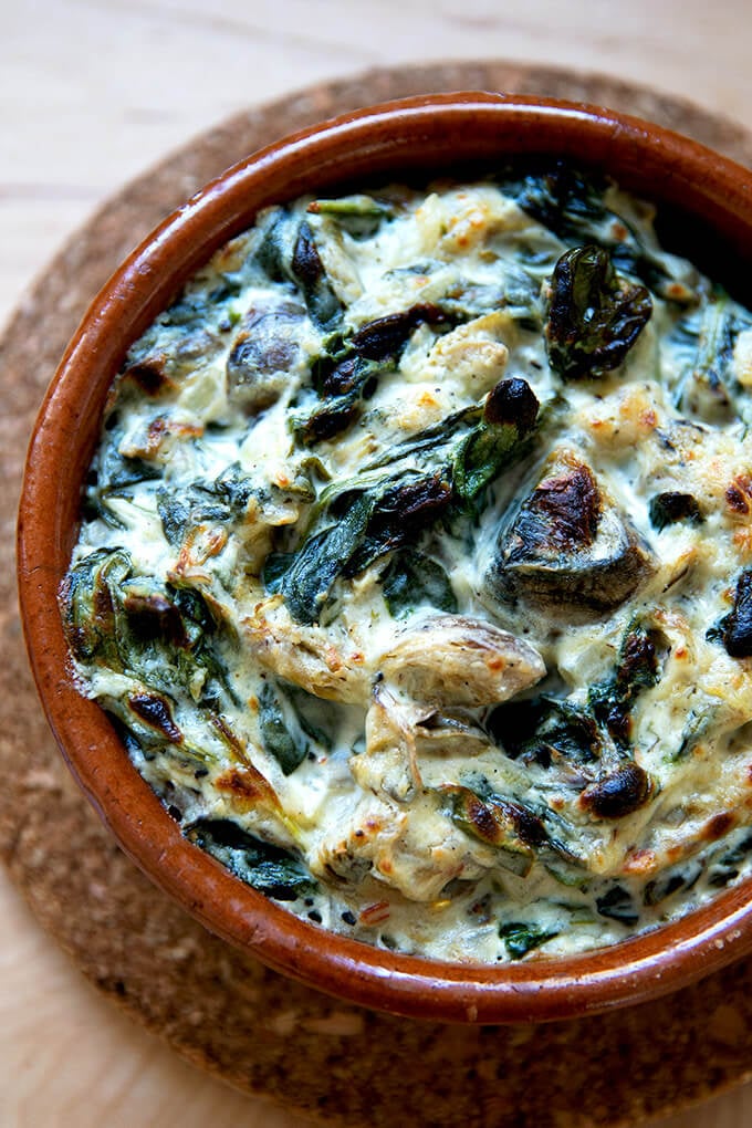 A small dish filled with spinach-artichoke dip just broiled.