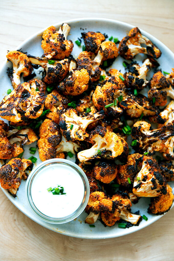 A large platter filled with buffalo cauliflower aside blue cheese dip.