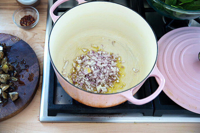 A large pot filled with olive oil, shallots, and salt.