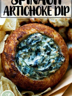 A bread bowl filled with spinach artichoke dip.