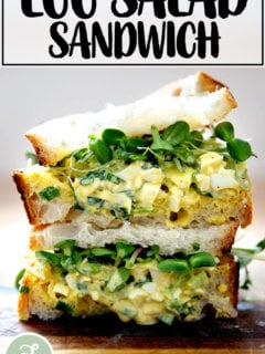 An egg salad sandwich on a board.