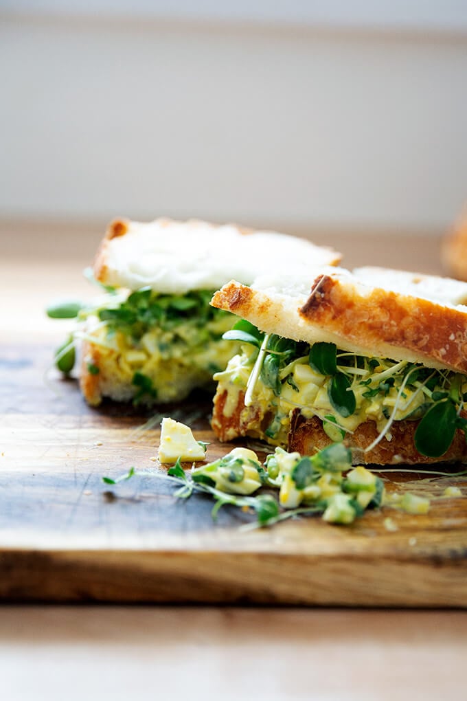 Egg salad sandwich on a board.