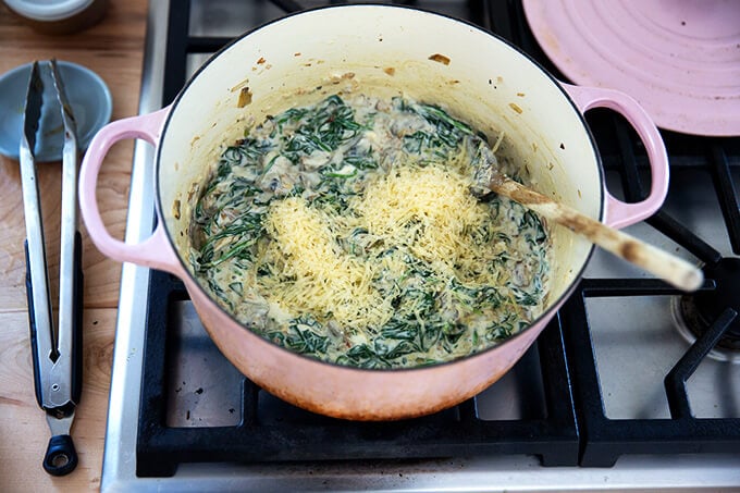 A large pot filled with spinach artichoke dip with parmesan just added.