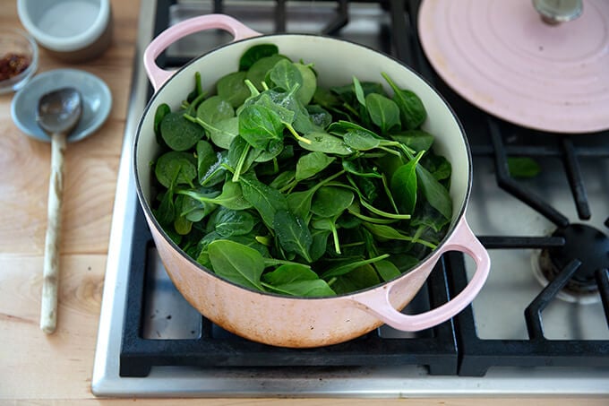 A Dutch oven filled with spinach.