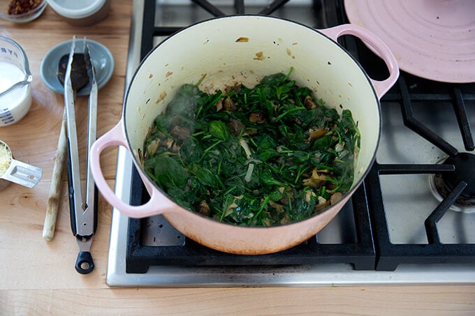 A pot of wilted spinach and artichoke hearts.