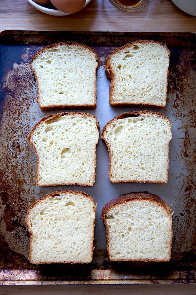 Six slices of brioche on a sheet pan.