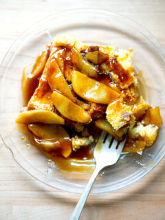 A plate of brioche bread pudding topped with apples sautéed in butter and caramel sauce.