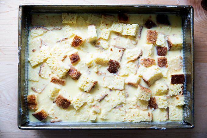 A 9x13-inch pan filled with toasted brioche cubes soaked in a custard after 30 minutes.