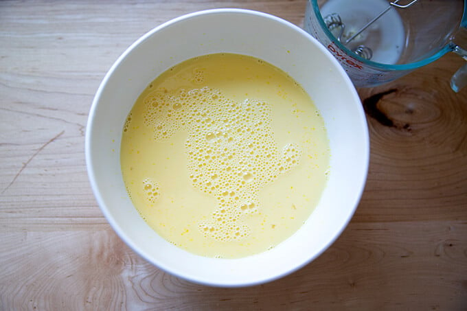 A bowl filled with the custard to make brioche bread pudding.