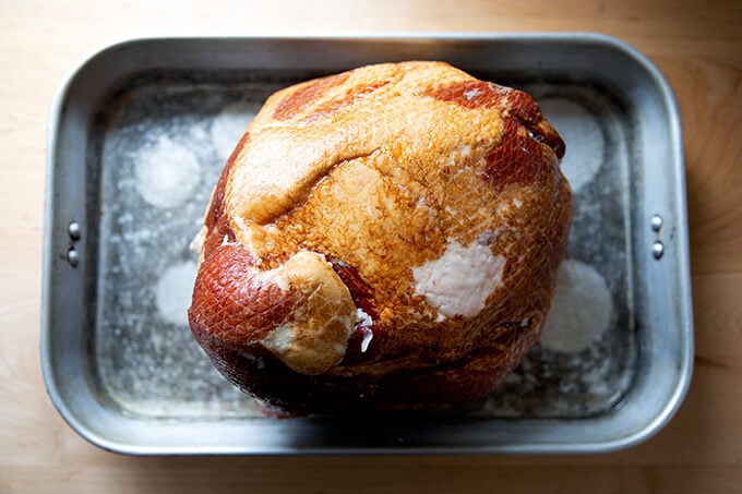 A ham, fat side up, in a roasting pan with a little bit of water.