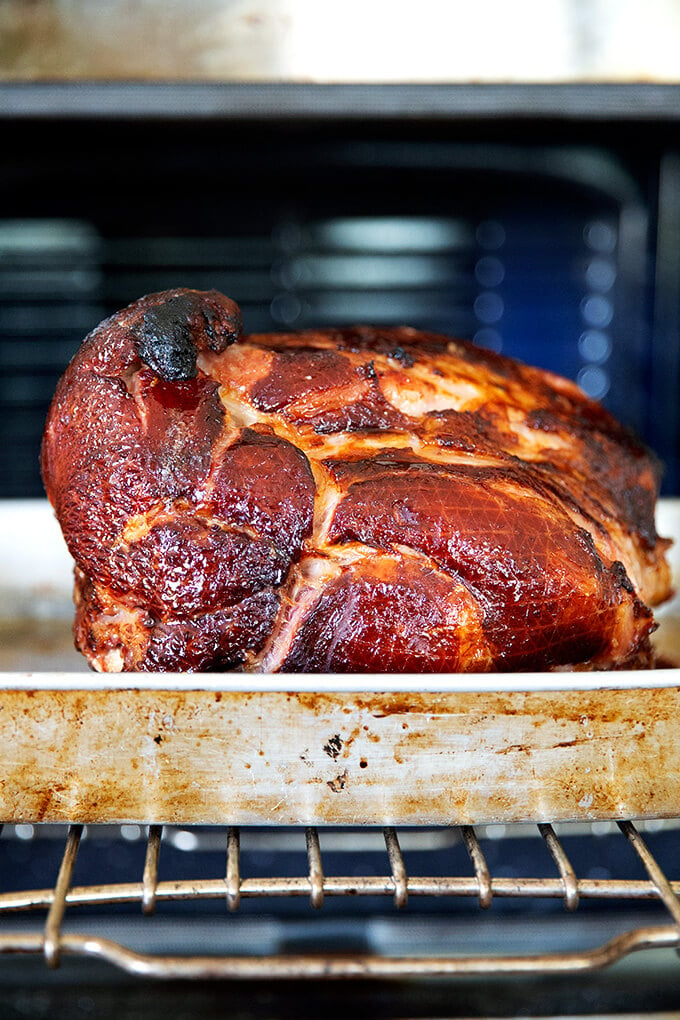 A brown sugar glazed ham coming out of the oven.