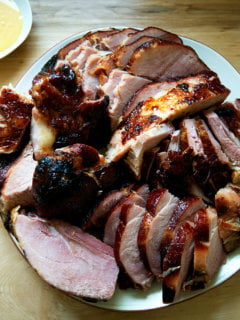 A carved brown sugar glazed ham on a platter.