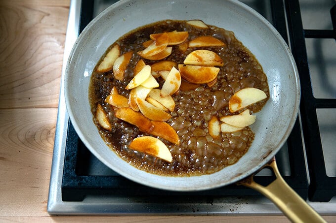 A sauté pan filled with apples and caramel sauce.