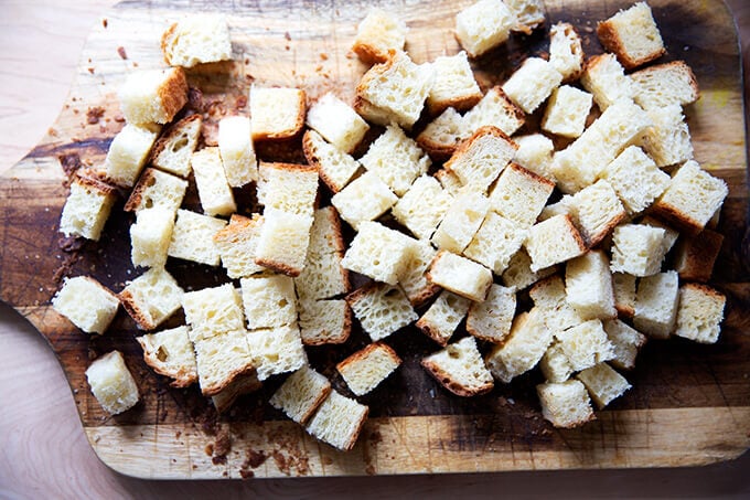 Cubes of toasted brioche bread on a cutting board.