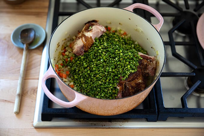 A large pot will with vegetables, a ham bone, and green split peas.