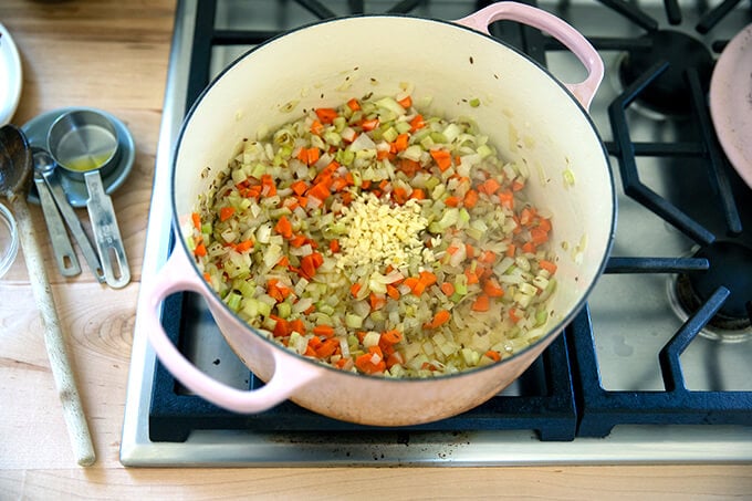 A large pot filled with sautéed mirepoix and garlic.