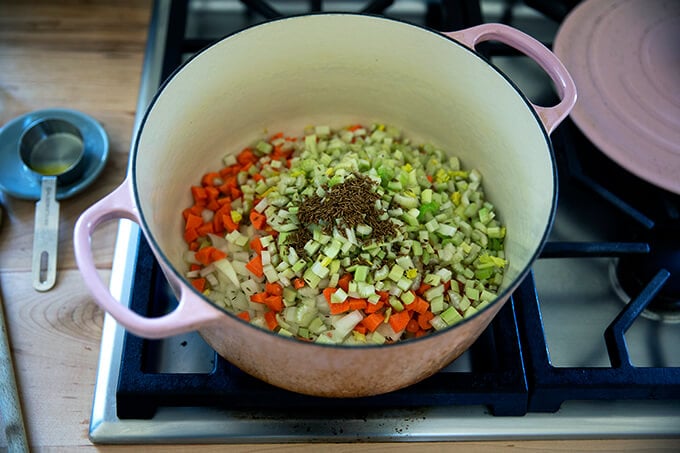 A large pot with onions, celery, carrots and cumin seed.