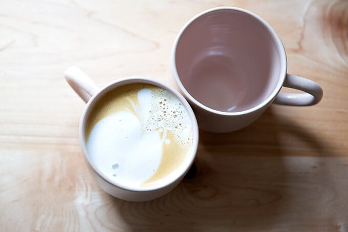 Two pink mugs, overhead shot, one holding a latté.