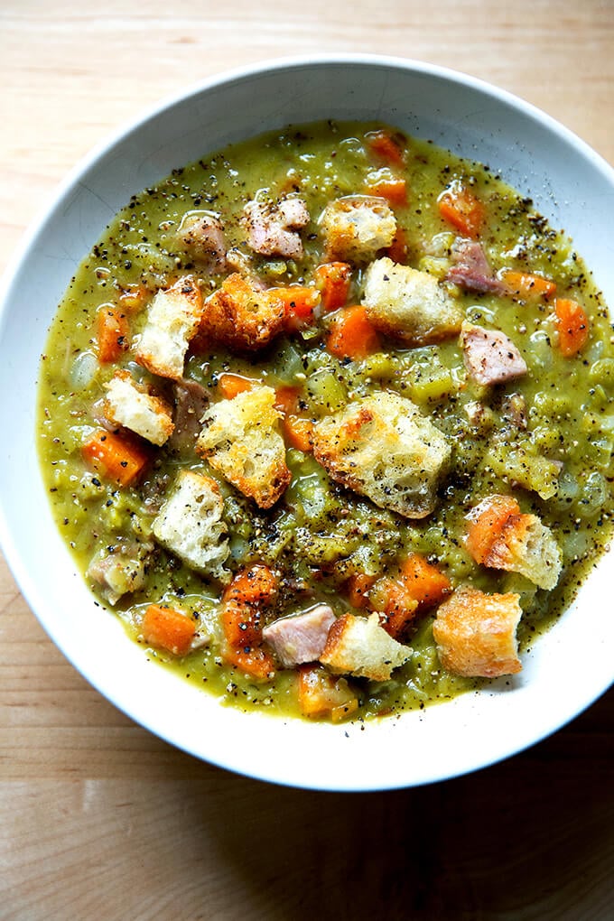 A bowl of split pea and ham soup topped with olive oil croutons.