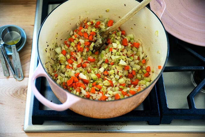 A large pot with sautéed carrots, onions, and celery.