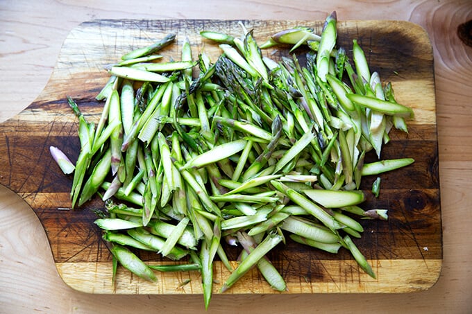 Thinly sliced asparagus on a board.