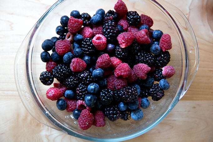 A mic of blackberries, raspberries, and blueberries in a glass bowl. 