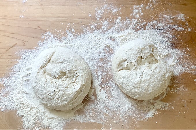 Two balls of ciabatta dough on a floured work surface. 