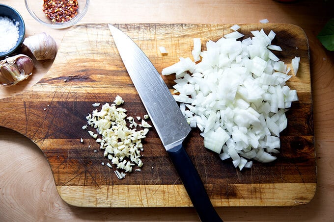 Minced onions and garlic on a cutting board.