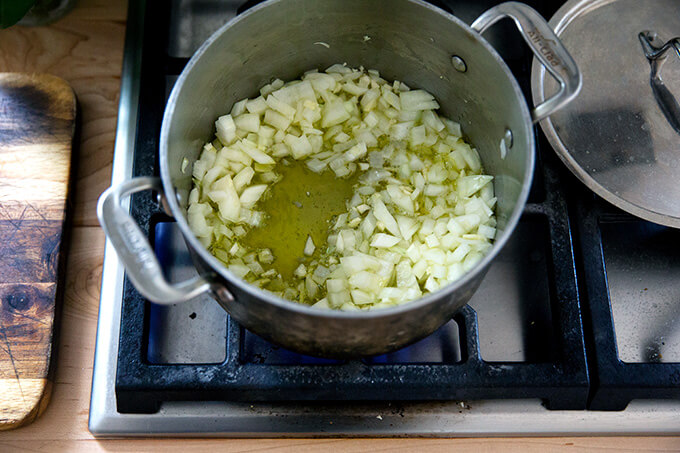 A pot of minced onions and garlic simmering stovetop.