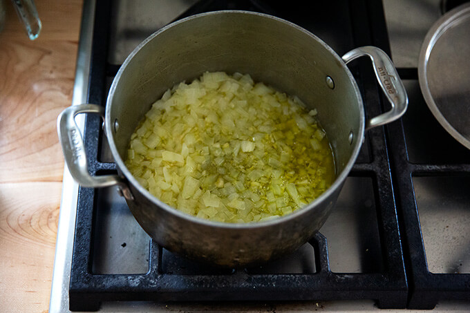 A pot of minced onions and garlic simmering stovetop with olive oil.