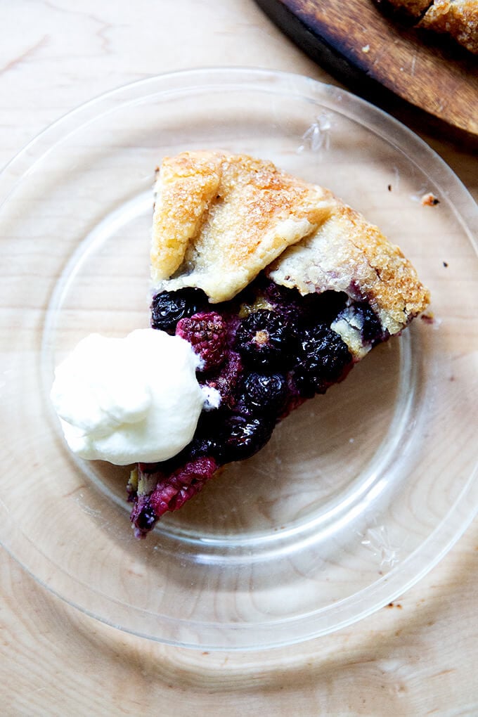 A slice of mixed berry galette on a plate with a dollop of whipped cream on top.