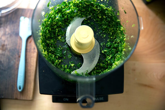 A food processor with pulsed basil and garlic.