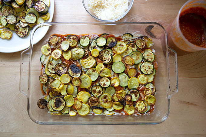 A 9x13-inch pan filled with layers of summer squash, tomato sauce, and parmesan.