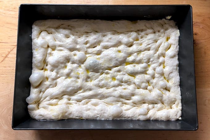 Unbaked Detroit-style pizza dough stretched edge to edge in a 10x14-inch pan. - 12