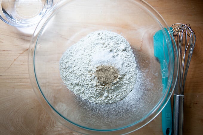 A large glass bowl filled with flour, salt and yeast.