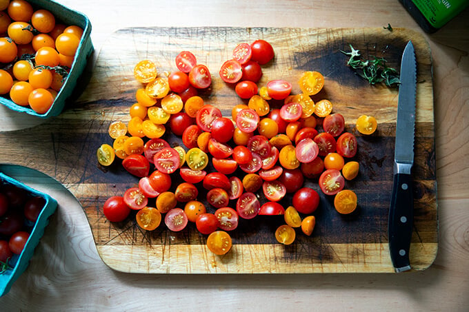 Halved cherry tomatoes on a board.