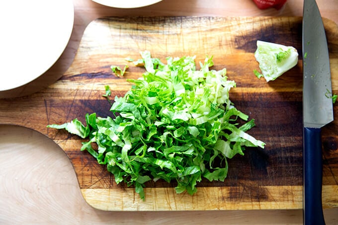 A head of Romaine lettuce on a cutting board, shredded. 