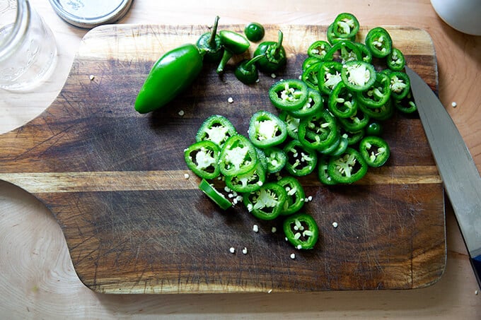 Sliced jalapeños on a board.