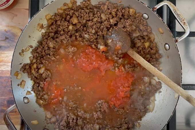 A sauté pan filled with taco meat ready to simmer. 