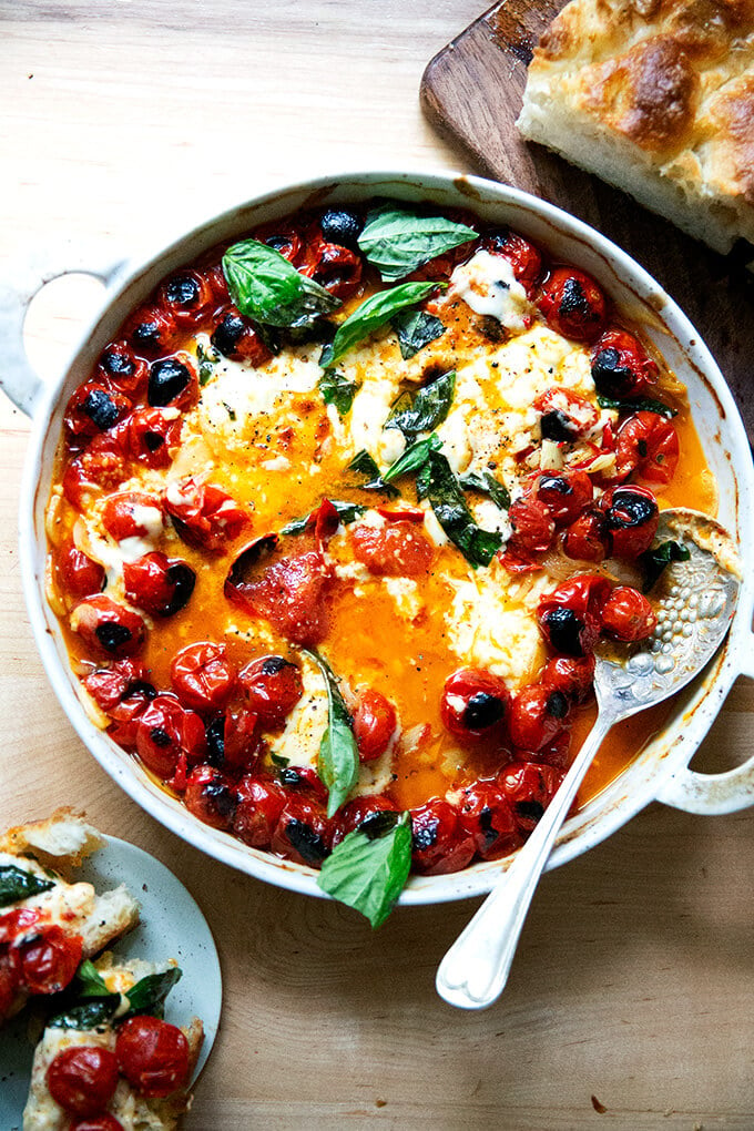 Baked feta and tomatoes aside bread and a plate.