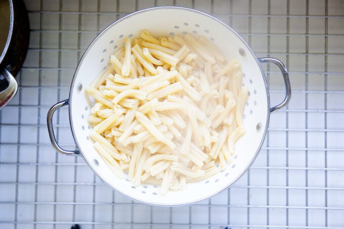 A colander in the sink holding just-cooked pasta.