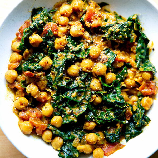A bowl of spicy chickpeas with tomatoes and kale.