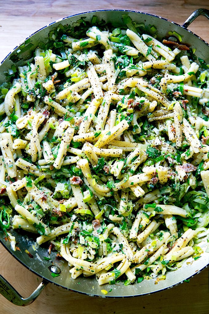 A skillet of pasta carbonara with leeks and lemon.