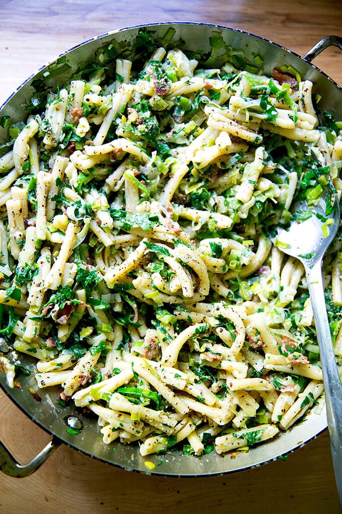 A skillet of pasta carbonara with leeks and lemon.