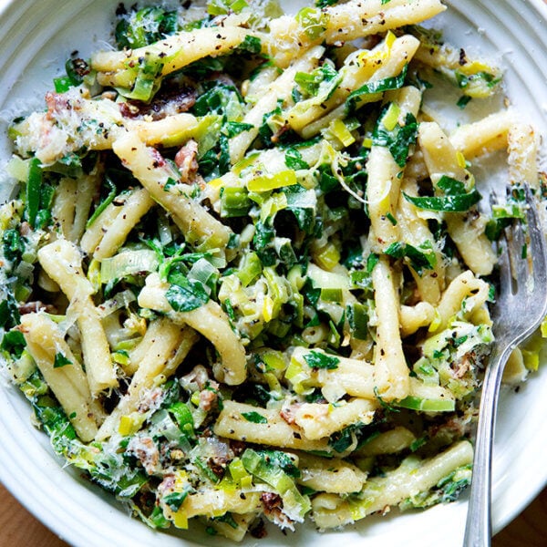 A plate of pasta carbonara with leeks and lemon on a plate.